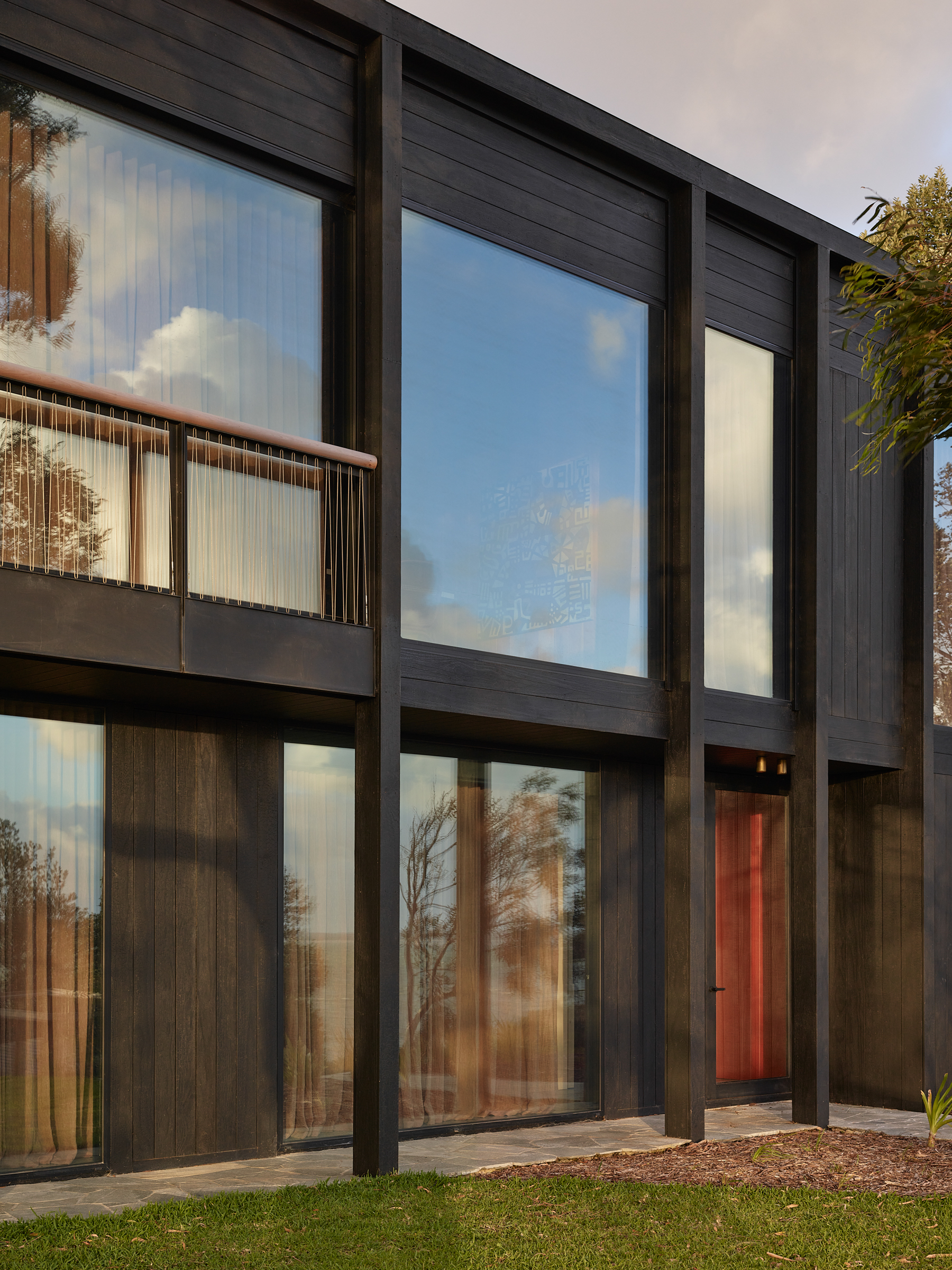 The facade of a two storey building with large glass windows that reflect the sky.