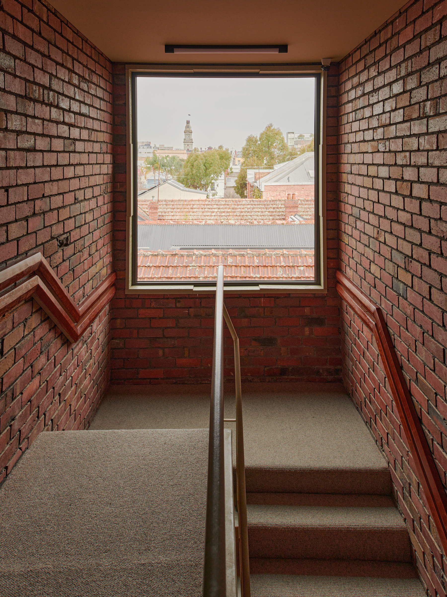 a brick staircase with a window looking out onto neighbouring roofs.