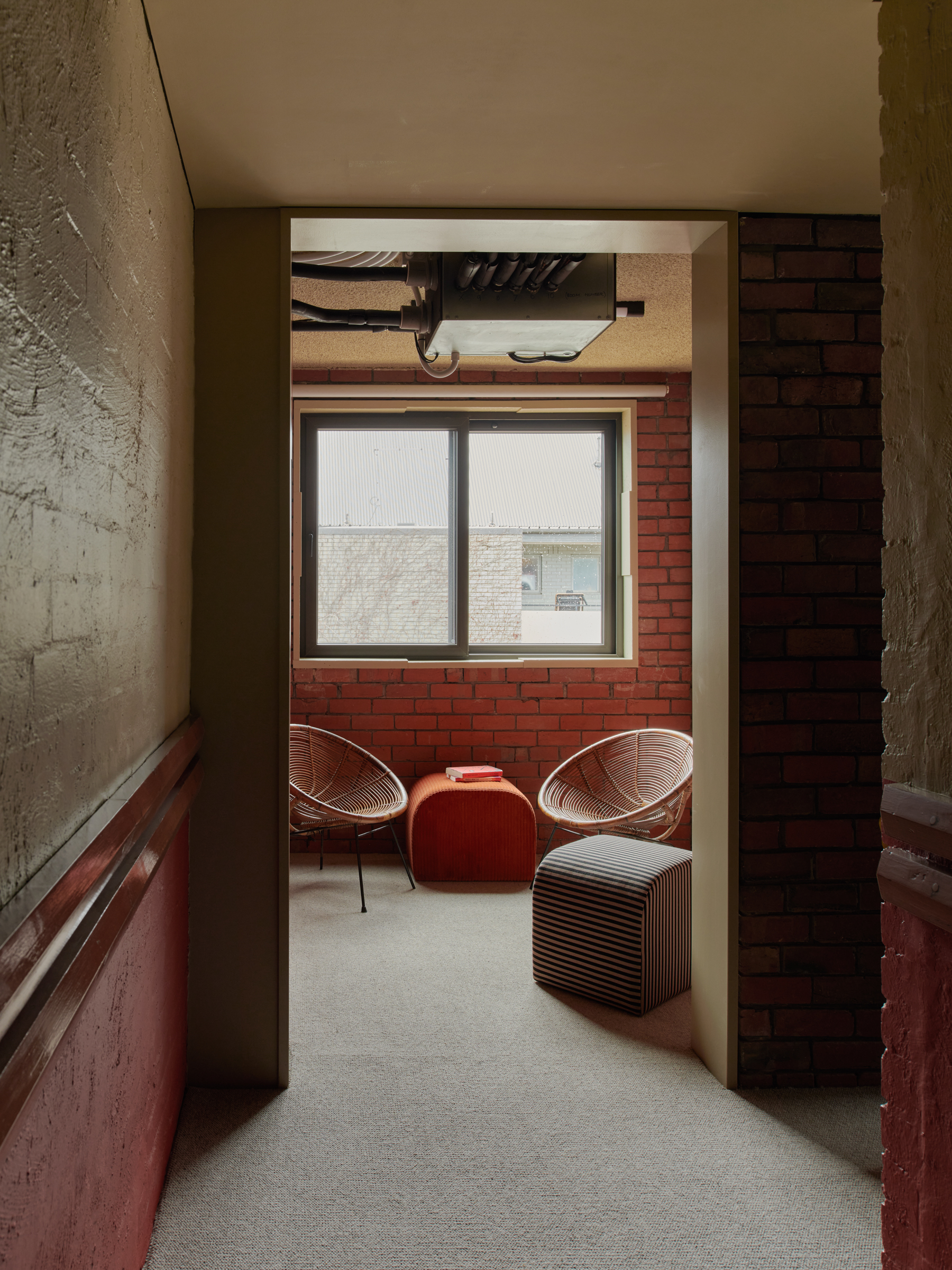 a small room adjacent to a hallway, with chairs and a window