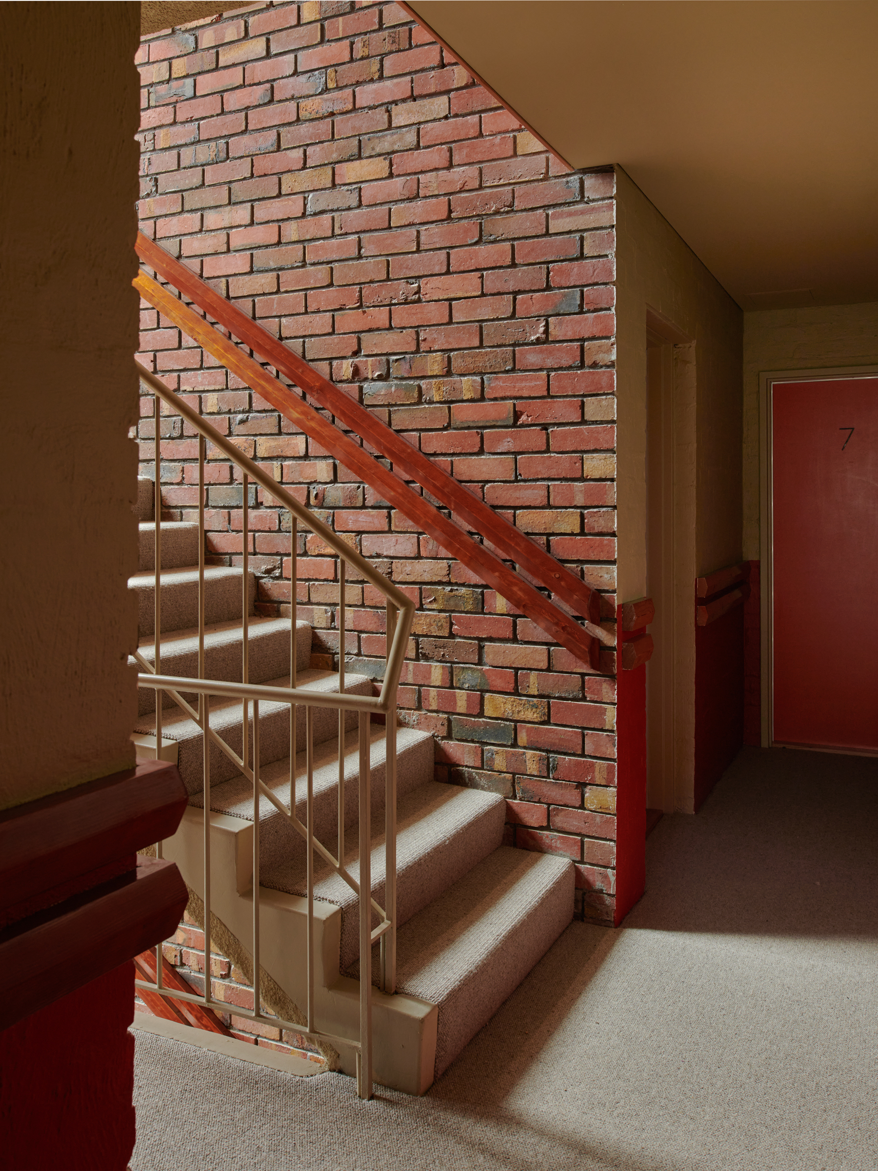 A staircase with brick walls, and an iron ballustrade.